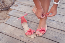 A Girl Putting On Coral Sandals At The Beach Sundeck