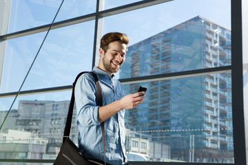 Attractive young man walking and looking at mobile phone