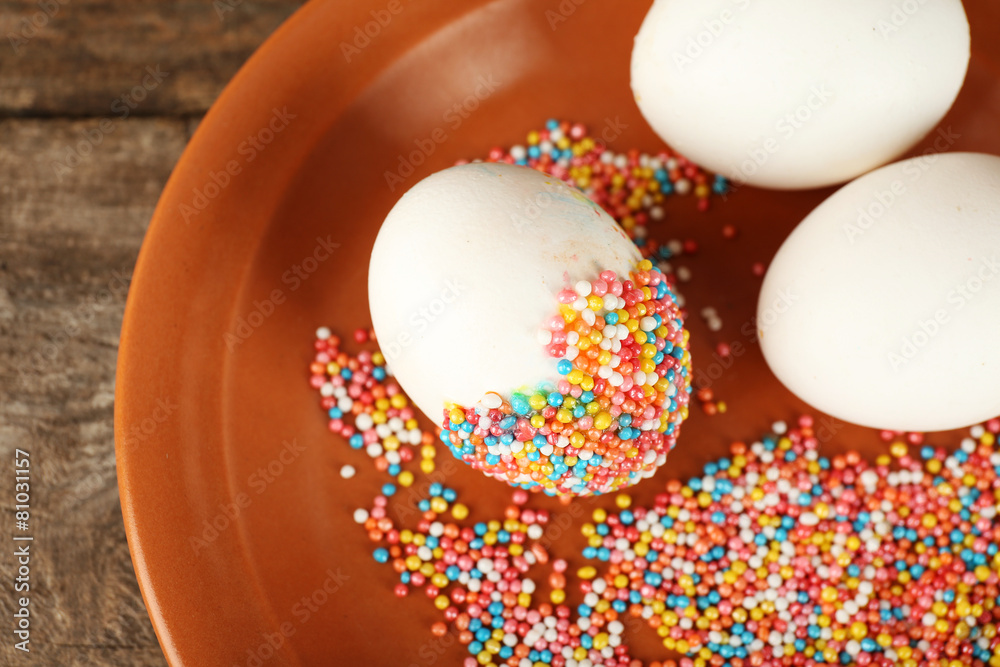 Decorating Easter eggs on color plate on wooden table, closeup