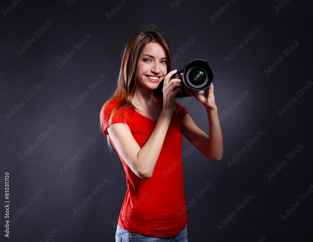 Young female photographer taking photos on black background