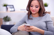 © shefkate - Pretty girl using her smartphone on  couch at home in the living