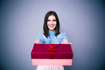 Poster - Smiling woman giving a gift box at camera