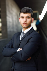 Wall Mural - Young businessman near a office building wearing black suit