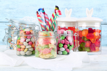 Sticker - Multicolor candies in glass jars on color wooden background