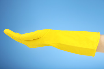 Rubber glove on hand, on blue background