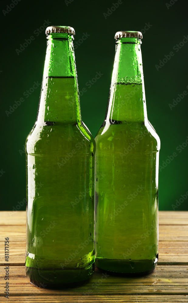 Glass bottles of beer on dark green background