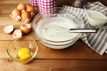 Wall Mural - Preparation cream with eggs in glass bowl on wooden background