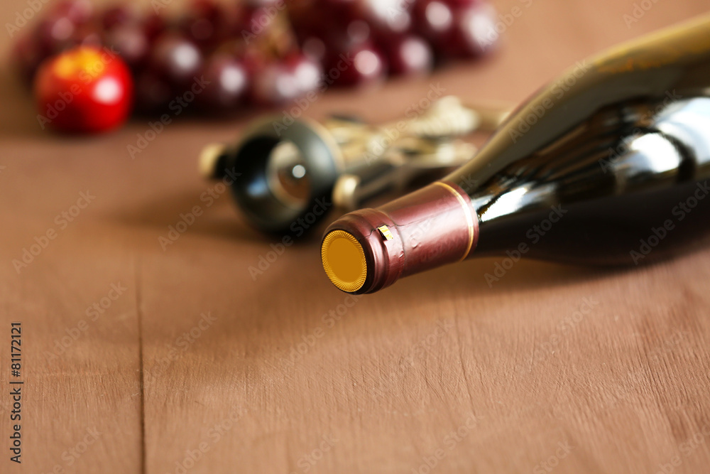 Bottle of red wine with grape on wooden background
