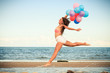 © Voyagerix - Girl jumping with colorful balloons on beach