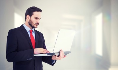 Poster - Composite image of focused businessman using his laptop