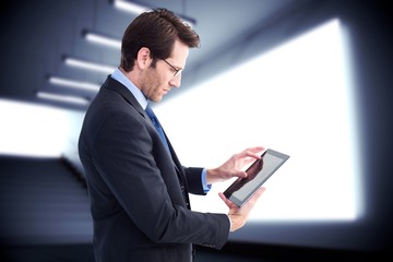 Poster - Composite image of businessman standing while using a tablet pc