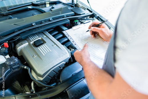 Fotografie, Obraz KFZ-Mechaniker mit Checkliste in Autowerkstatt