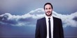 © WavebreakMediaMicro - smiling businessman in suit standing with hands in pockets