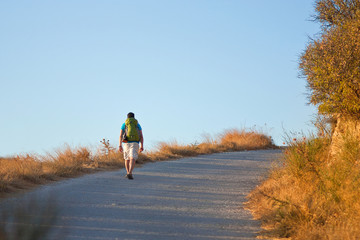 Man hiking the road at sunset