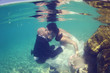 Bride and groom kissing underwater