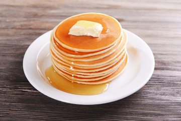 Wall Mural - Delicious pancakes with honey on plate on table close-up