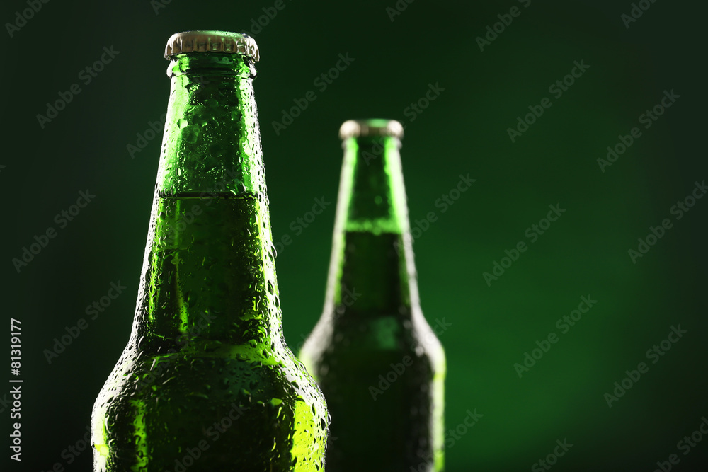 Glass bottles of beer on dark green background