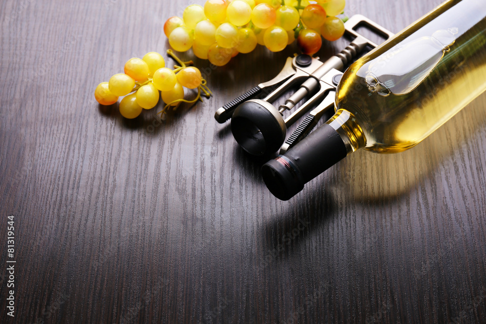 Bottle of wine with grape and corkscrew on wooden background