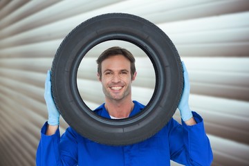 Poster - Composite image of confident mechanic looking through tire