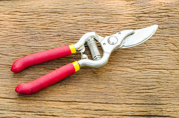 Red garden secateurs on old wooden table