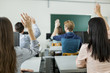 © NDABCREATIVITY - Young students raising hands in a classroom