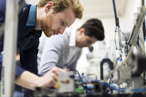 Cuadros en Lienzo Two young handsome engineers working on electronics components