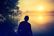 Man Watching A Sunrise Over Lake. Human Silhouette.