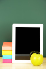 Canvas Print - Tablet on table, on green blackboard background