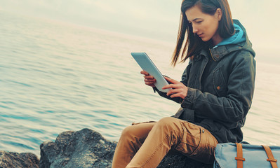 Sticker - Traveler girl sitting on coast with digital tablet