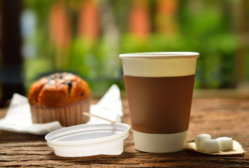 Paper cup of coffee and cake on wooden background