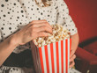 © LoloStock - Young woman eating popcorn in movie theater