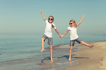 Wall Mural - two sisters playing on the beach