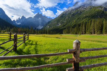 Fence on green pasture in Dolomites Mountains in summer, Italy