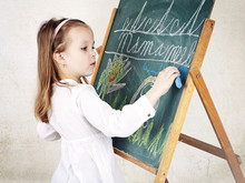 Little Girl Drawing A Picture With Chalk On The Blackboard