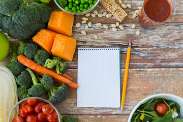 close up of ripe vegetables and notebook on table