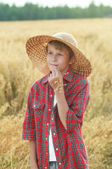 Teenage farm boy in wide-brimmed hat and oat cereal ears straw