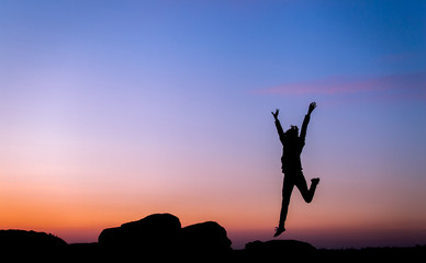 Silhouette of happy young woman jump against beautiful colorful