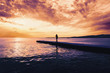 Woman walking on pier at sunset