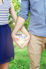 Poster - Loving couple holding hands in shape of heart, close-up