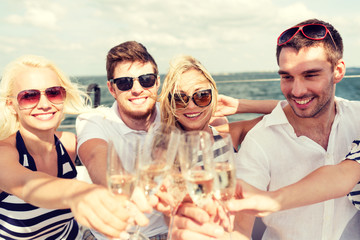 Poster - smiling friends with glasses of champagne on yacht