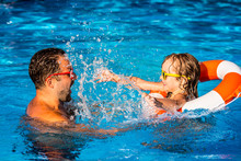 Child And Father Playing In Swimming Pool