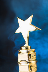 Wall Mural - gold star trophy against blue smoke background