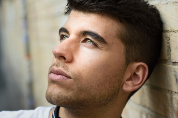 Handsome young man with blue eyes posing near a wall