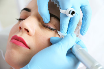 Cosmetologist applying permanent make up on eyes, close-up