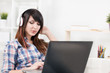 © Liudmila Dutko - Pretty young brunette listening music and typing in laptop