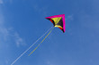 A colorful kite flying high in the bright blue sky.