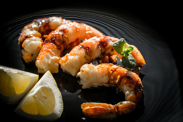 Wall Mural - Fried shrimps with lemon wedges on the black background