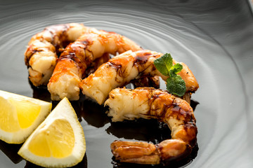 Wall Mural - Fried shrimps with lemon wedges on the black background