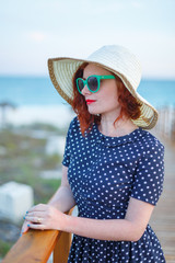 Wall Mural - Red-haired girl in a hat and sunglasses