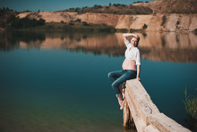 Beautiful Young Pregnant Woman Sitting On The Pier On Blue Lake